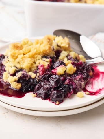 Blueberry crumble on a plate with big juice blueberries and sweet crumble topping.