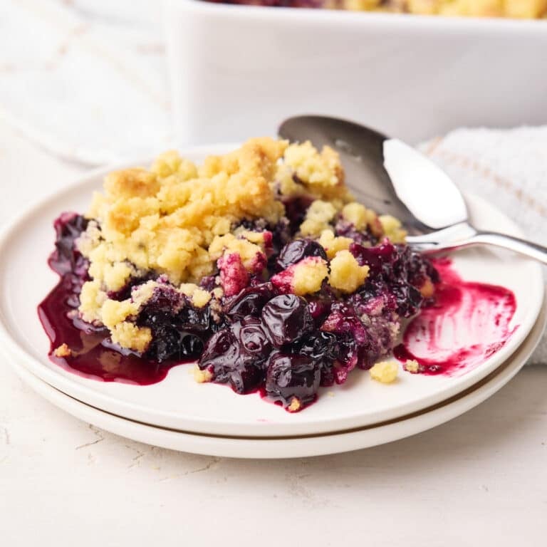 Blueberry crumble on a plate with big juice blueberries and sweet crumble topping.