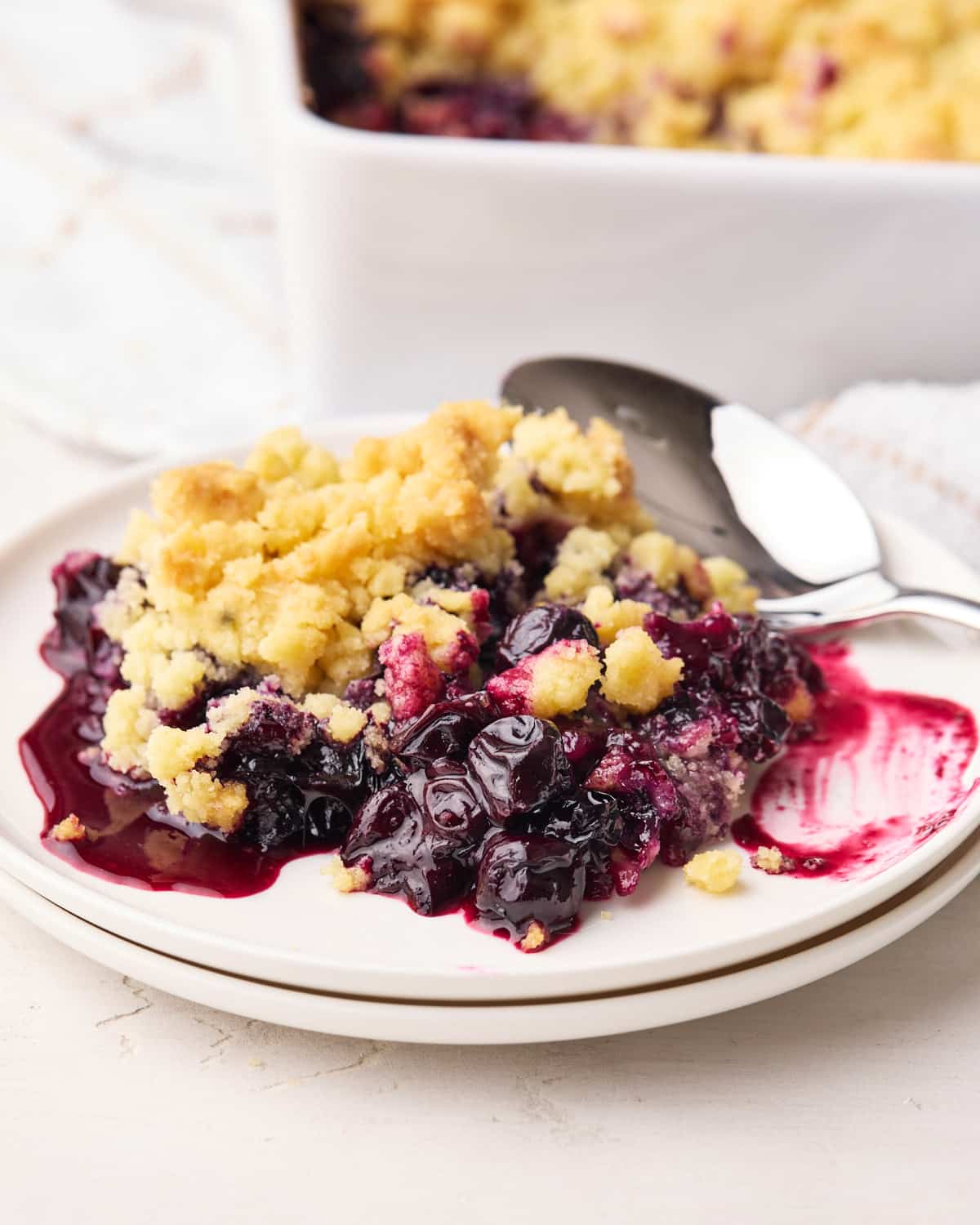 Blueberry crumble on a plate with big juice blueberries and sweet crumble topping.