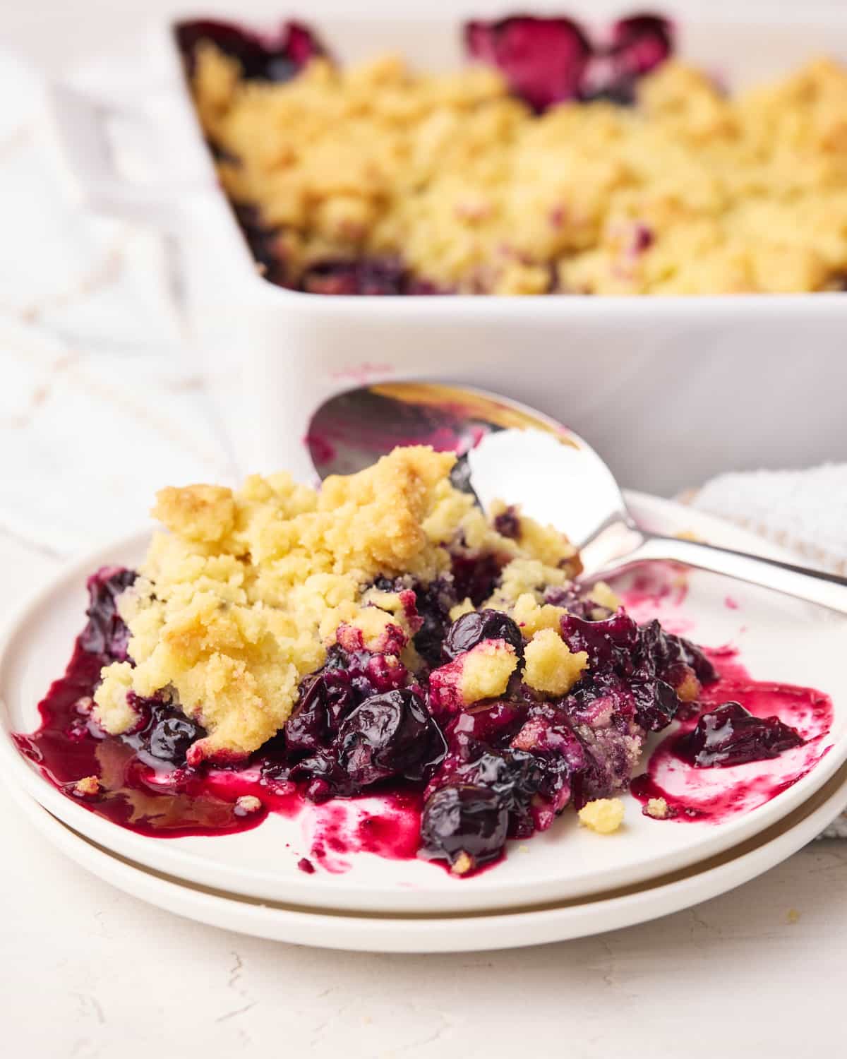 Blueberry crumble on a plate with big juice blueberries and sweet crumble topping.