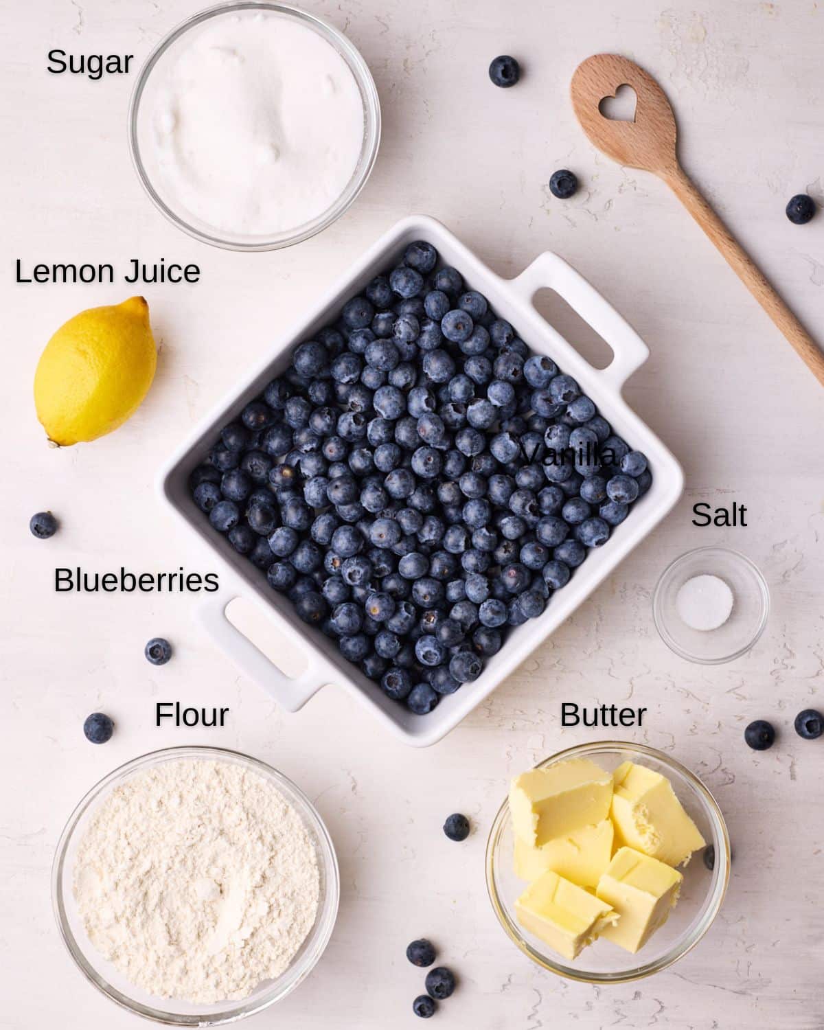 Ingredients to make blueberry crumble - fresh blueberries, flour, sugar, butter, lemon juice, and salt. 