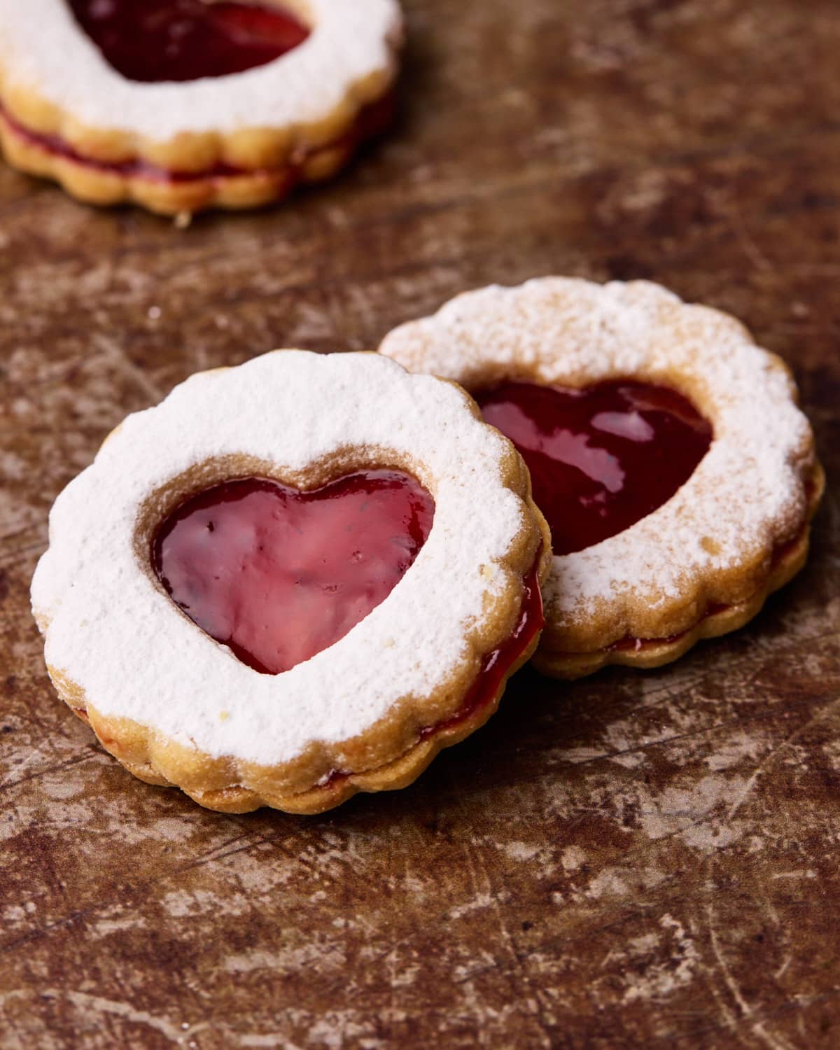 Two Linzer cookies, one slightly leaning on the other.