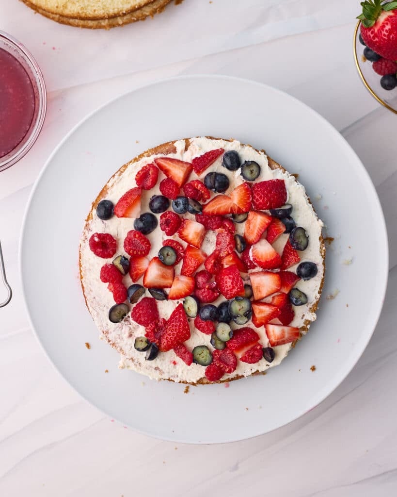 Chantilly cream spread on the sponge with berries layered on top.
