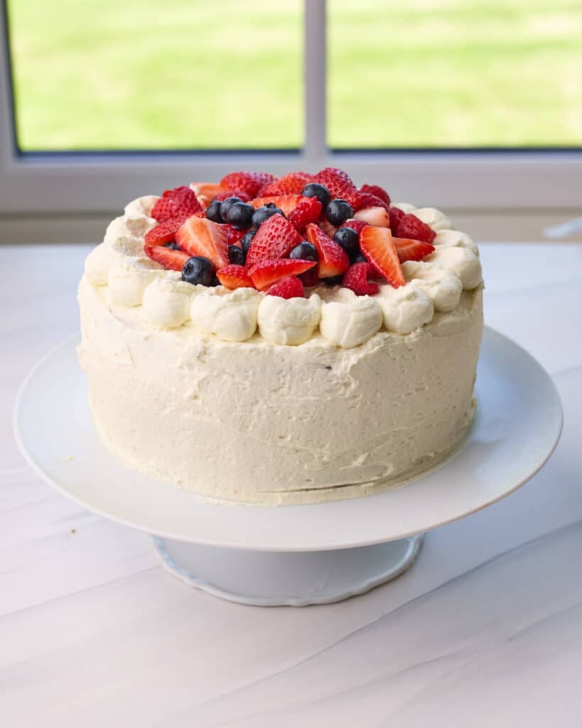 Finished cake decorated with piped cream and berries on top. 