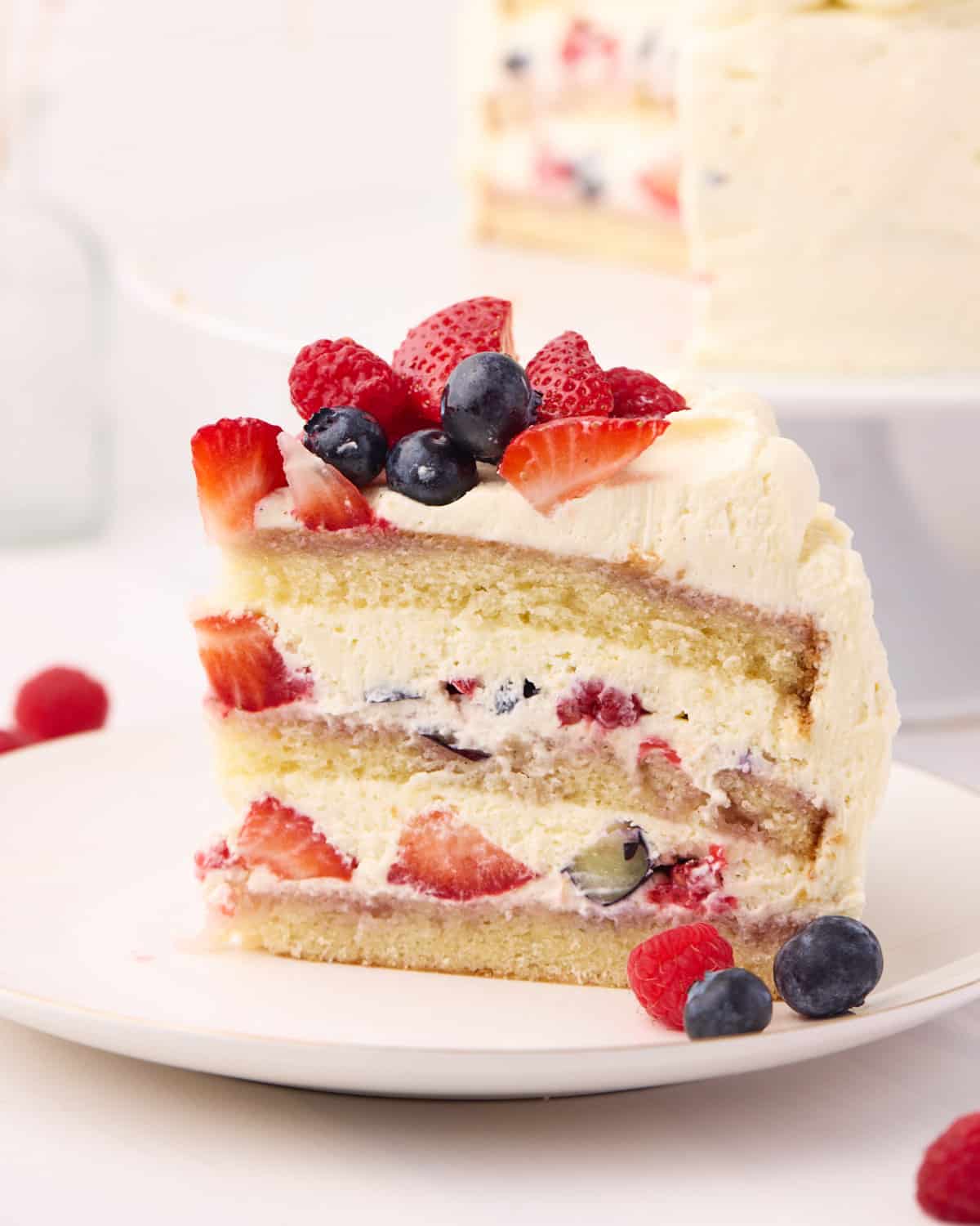 Side view of a slice of berry chantilly cake, showing the layers of fresh berries and chantilly cream inside.