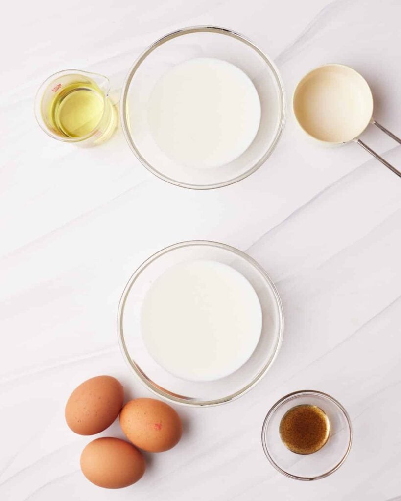 Milk in two bowls, with oil, eggs and vanilla sat next to them.
