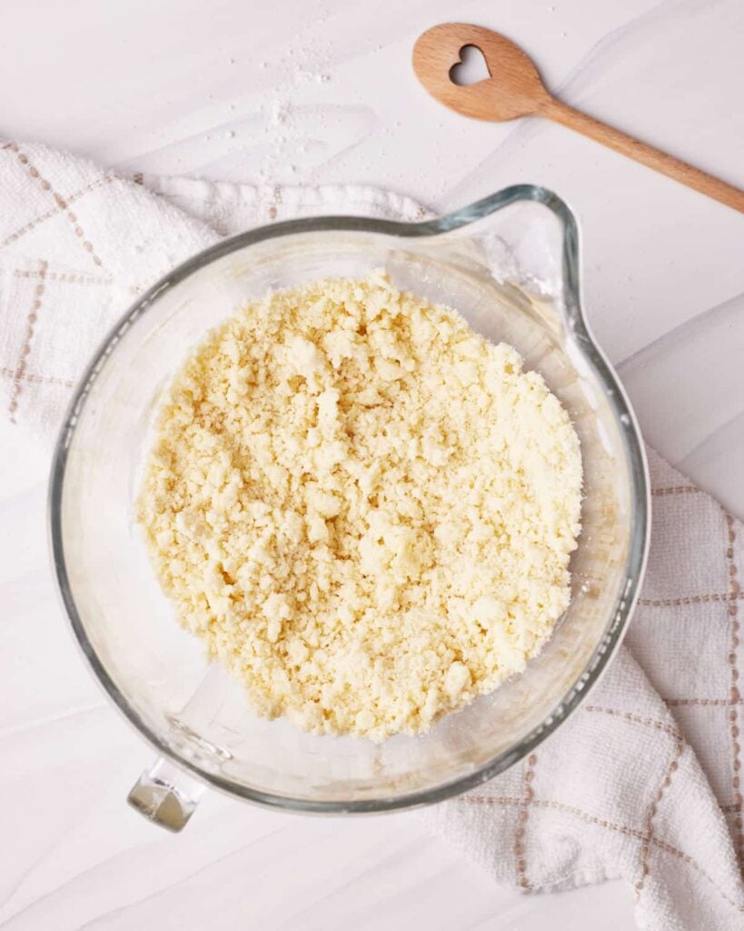 Crumbly butter mixture in a stand mixer bowl. 