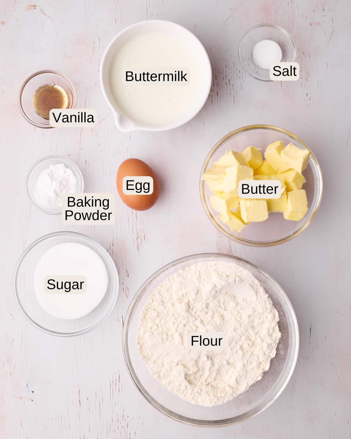Labelled ingredients for scones, including salt, buttermilk, vanilla, an egg, butter, baking powder, sugar, and flour.