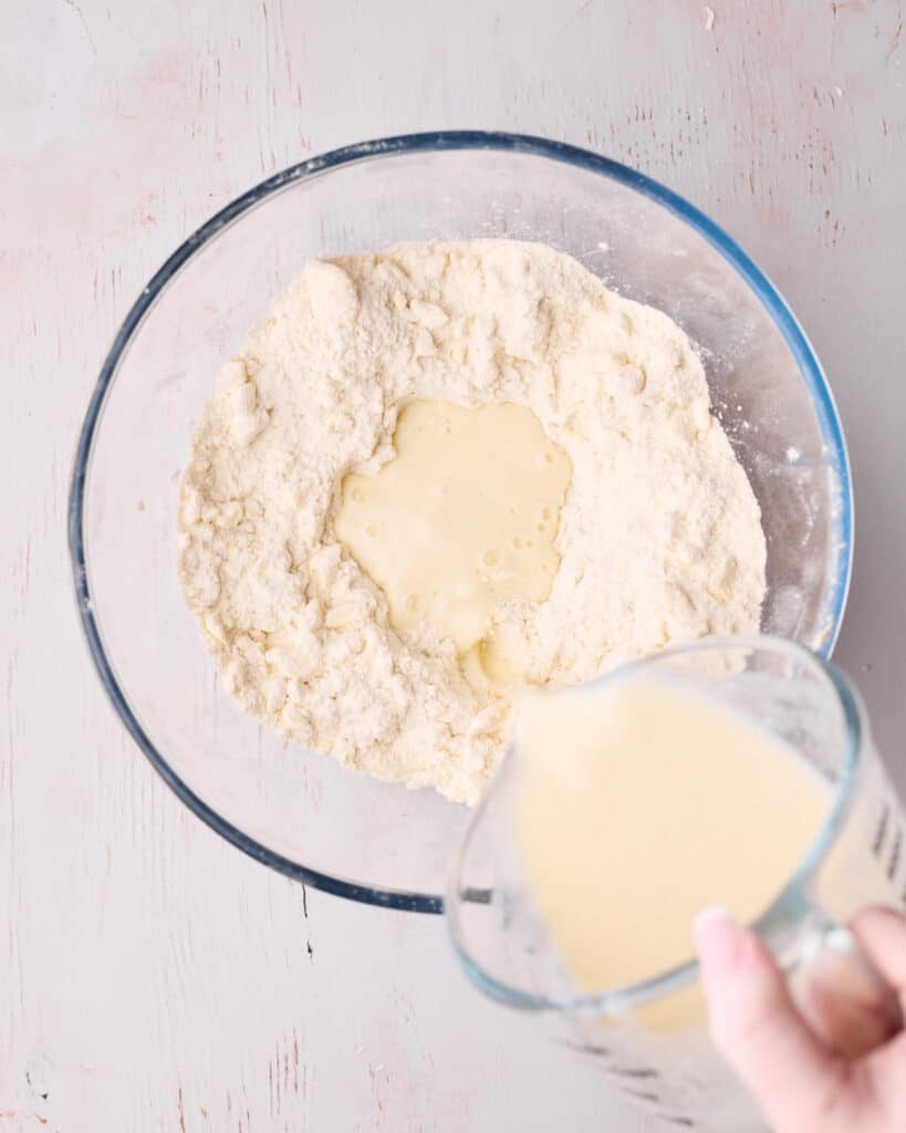 Wet ingredients, including egg, buttermilk, and vanilla being added to the flour mixture.