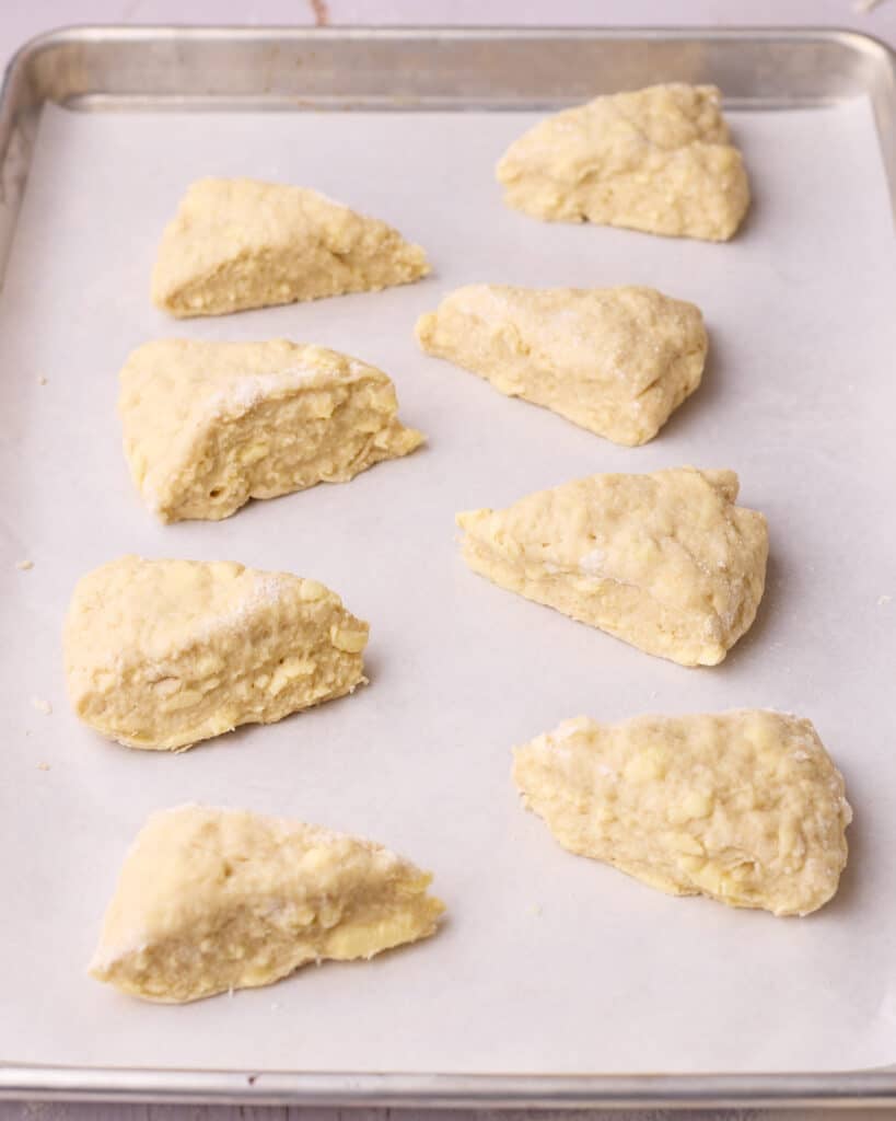 Slices of dough spaced out on a lined baking sheet after chilling.