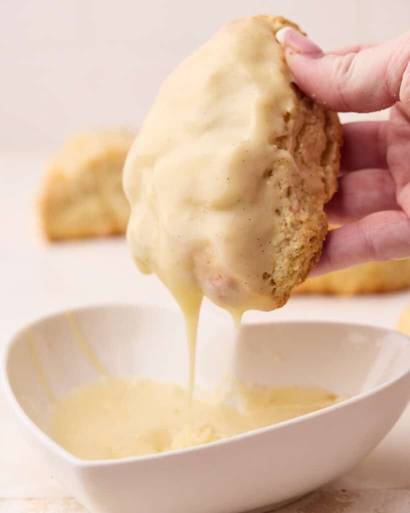 Scone being dipped into a glaze.
