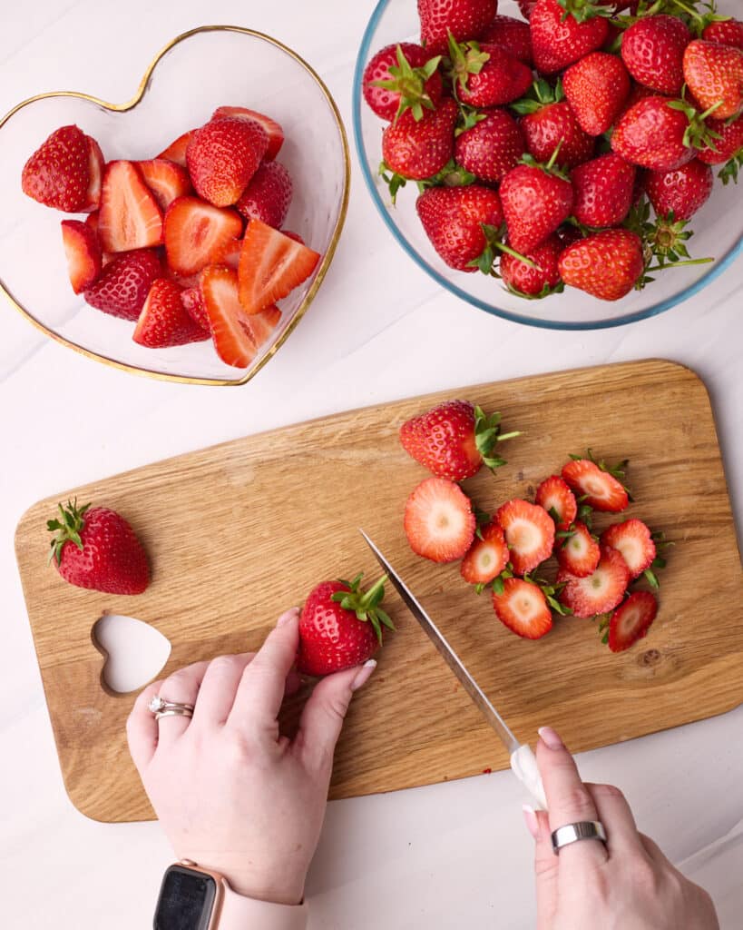 Strawberries being hulled with a knife for strawberry pie filling.