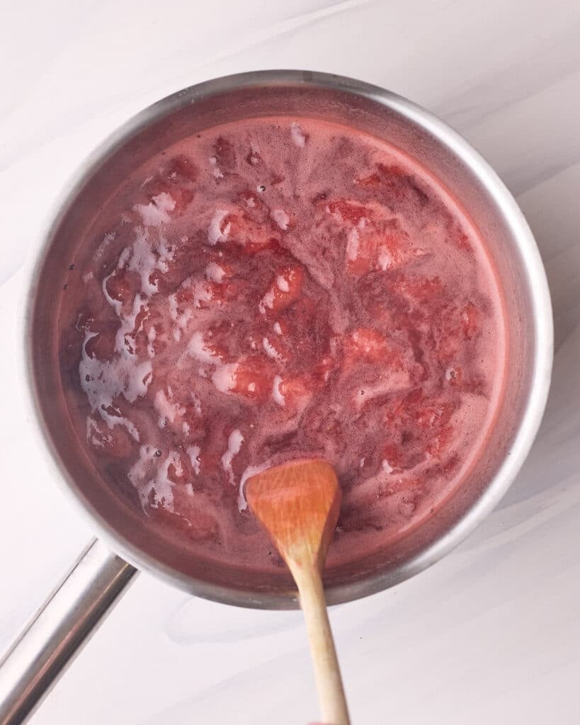 Strawberry sugar mixture being heated in a saucepan for strawberry pie filling.
