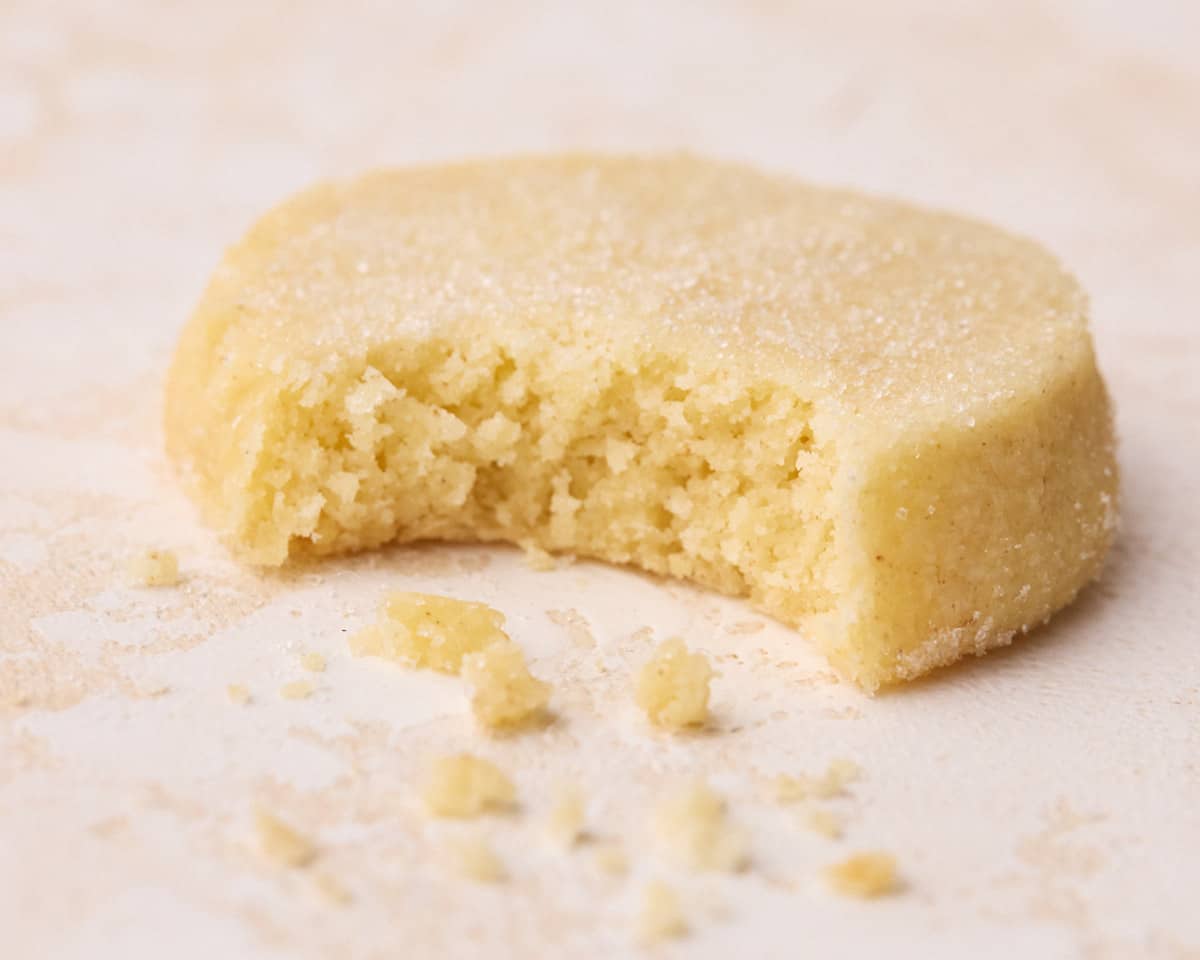 A close up of a shortbread cookie after being bitten into, showing the buttery, crumbly texture.