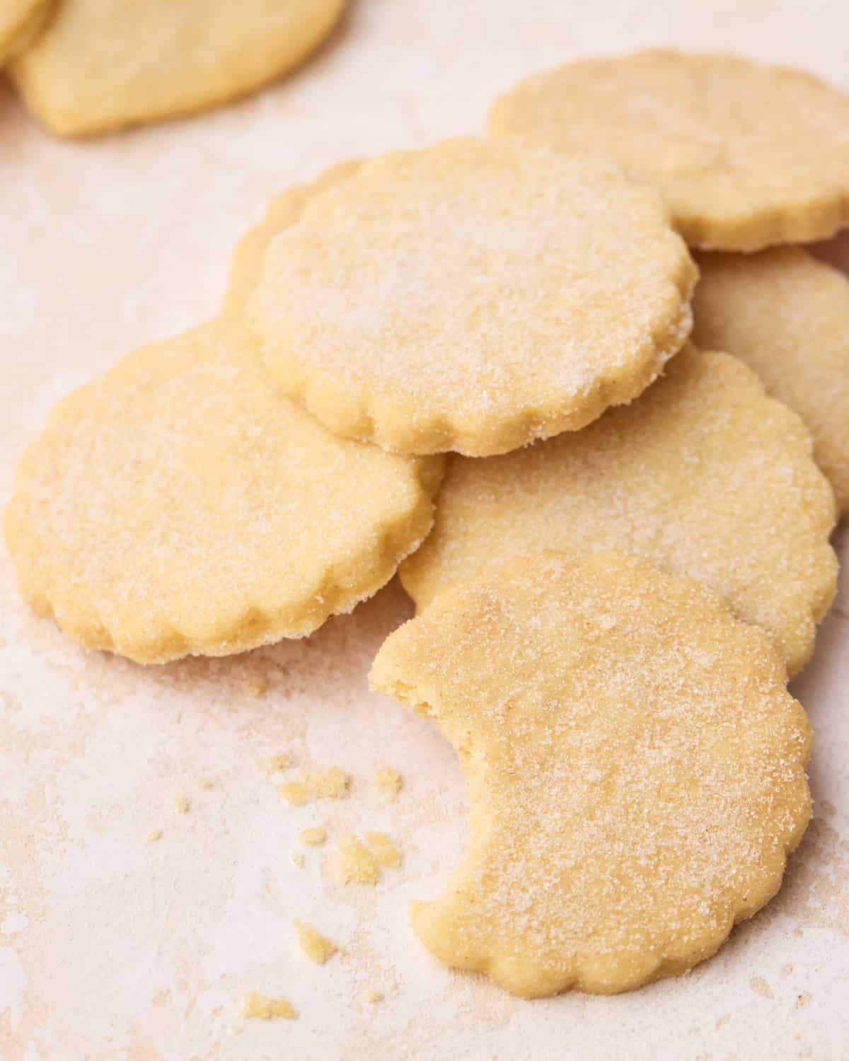 An overhead view of shortbread cookies, layered over each other, with a bite taken out of one.