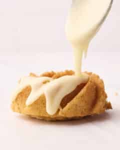 Vanilla glaze being drizzled over a mini bundt cake.