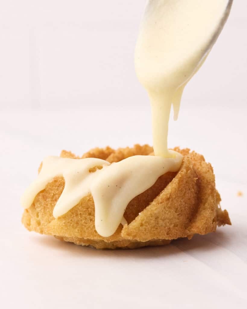 Vanilla glaze being drizzled over a mini bundt cake.