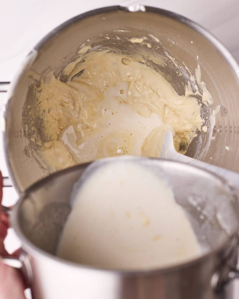 Pouring hot milk and butter into sponge cake batter to make a hot milk sponge cake.