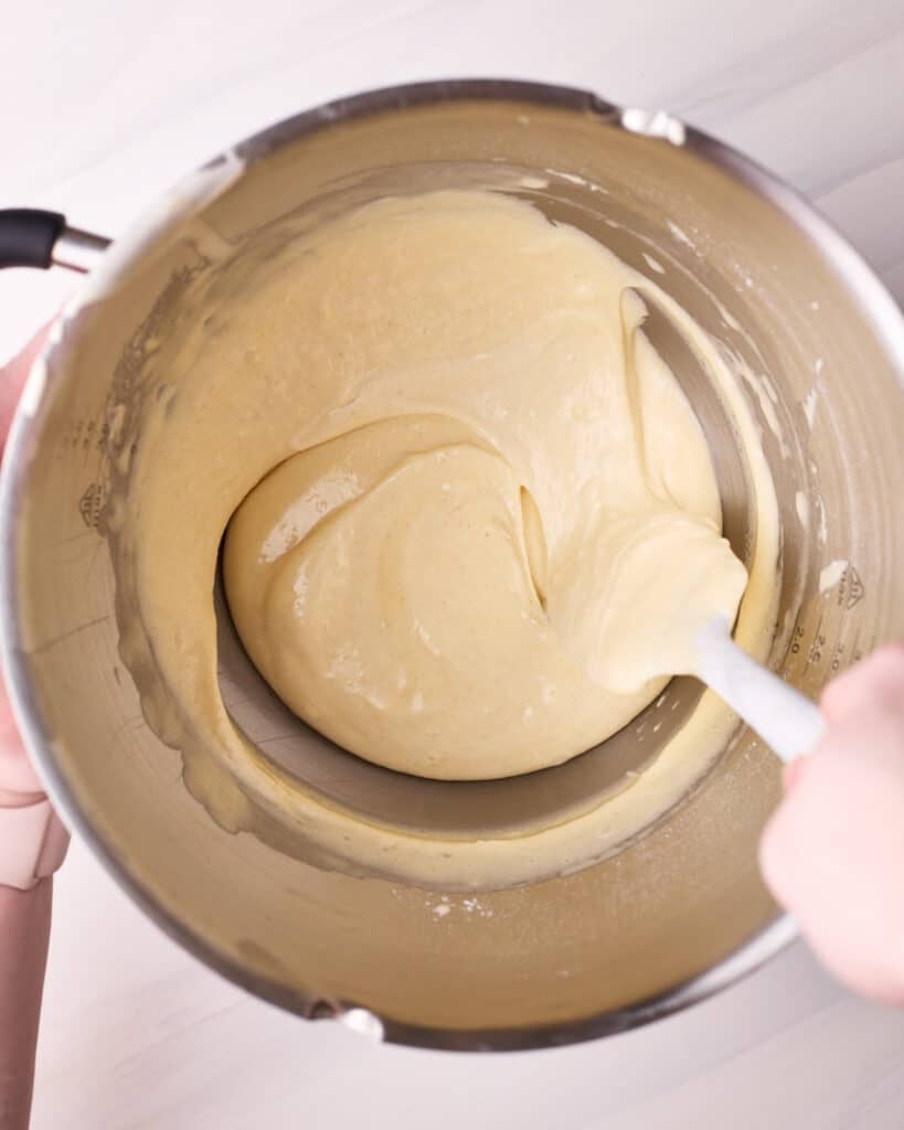 Folding hot milk mixture into sponge cake batter to make a hot milk cake. 