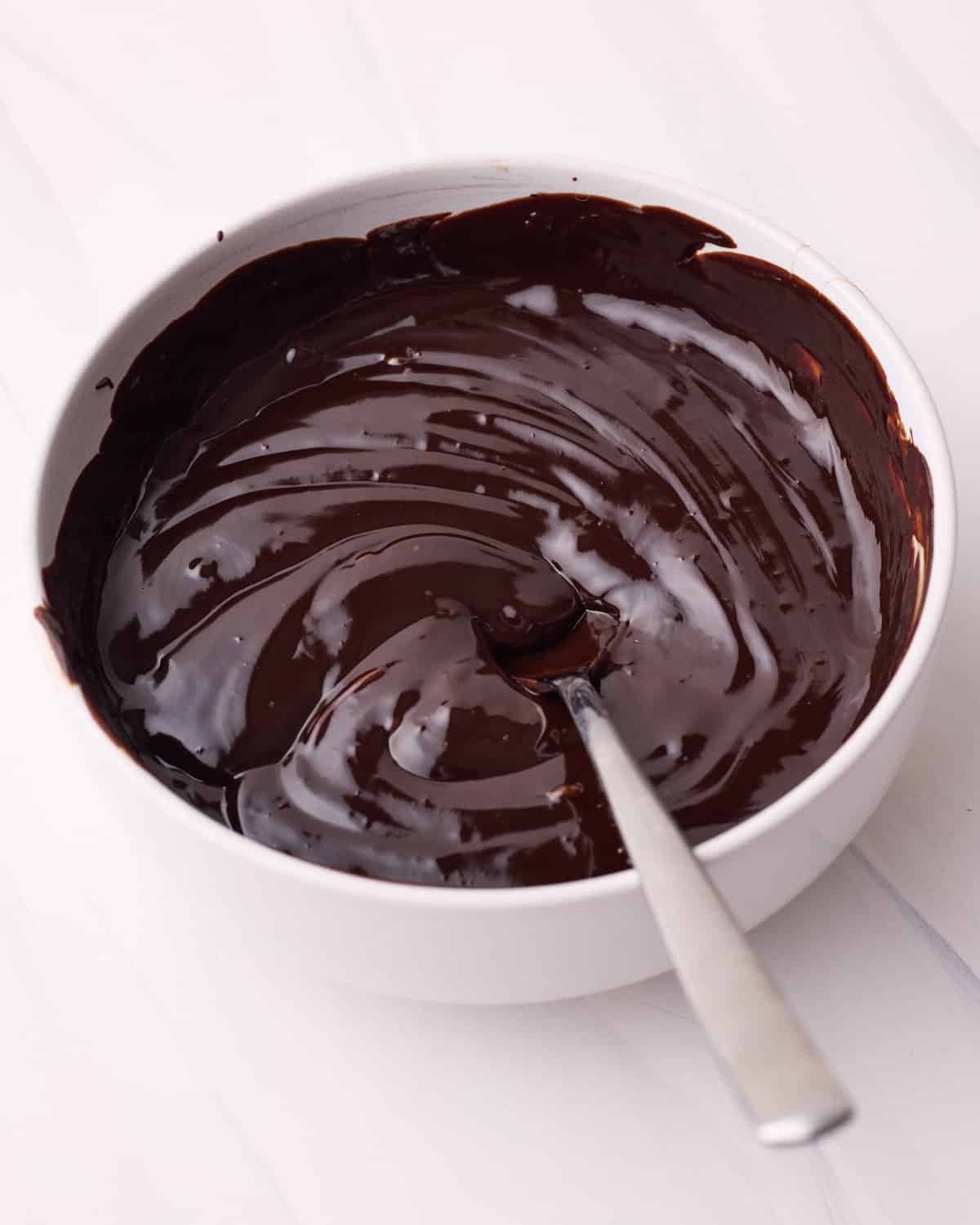 Shiny chocolate glaze for Boston cream pie being mixed together in a small bowl.