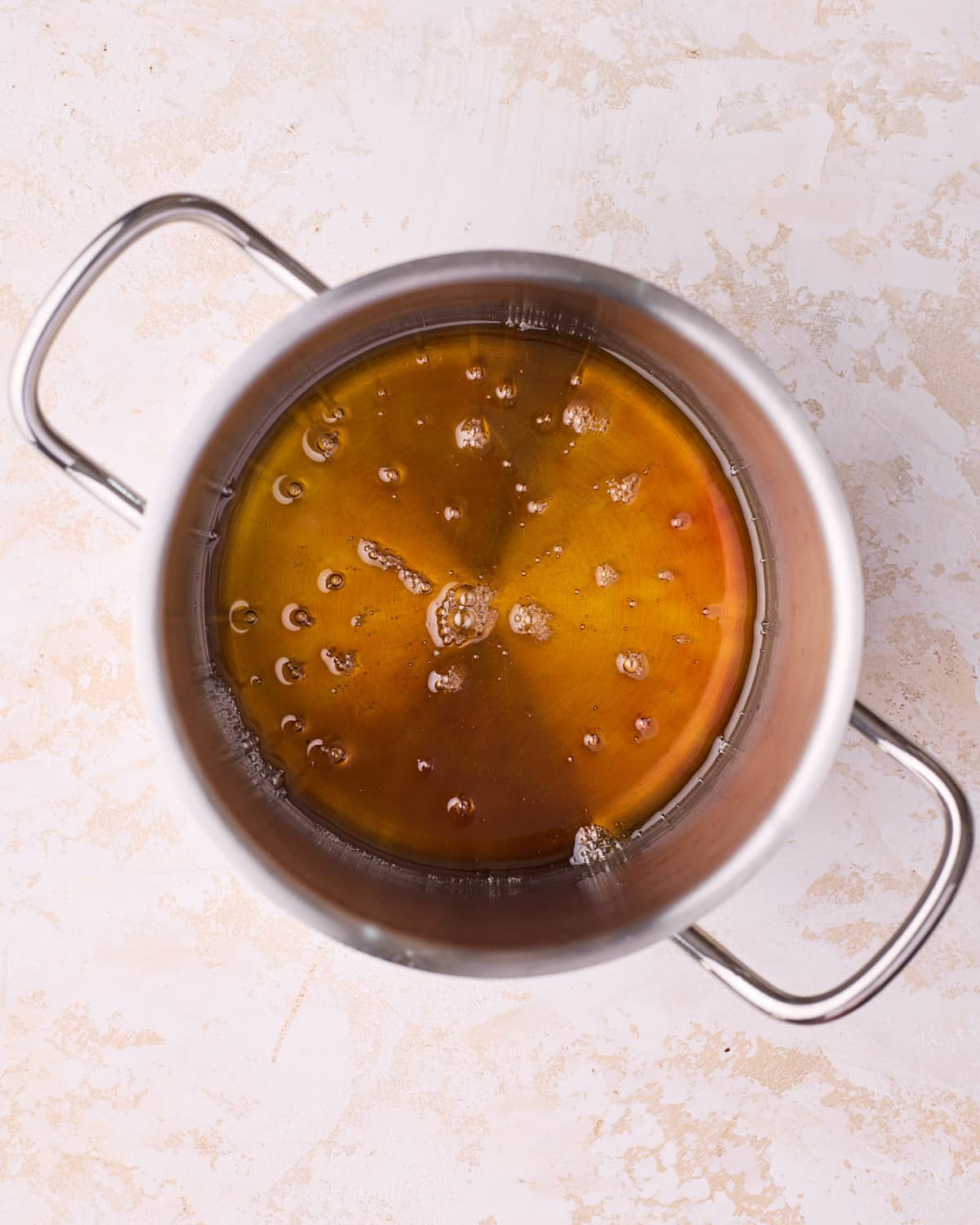 The color of homemade caramel when it is ready, in a stainless steel saucepan.