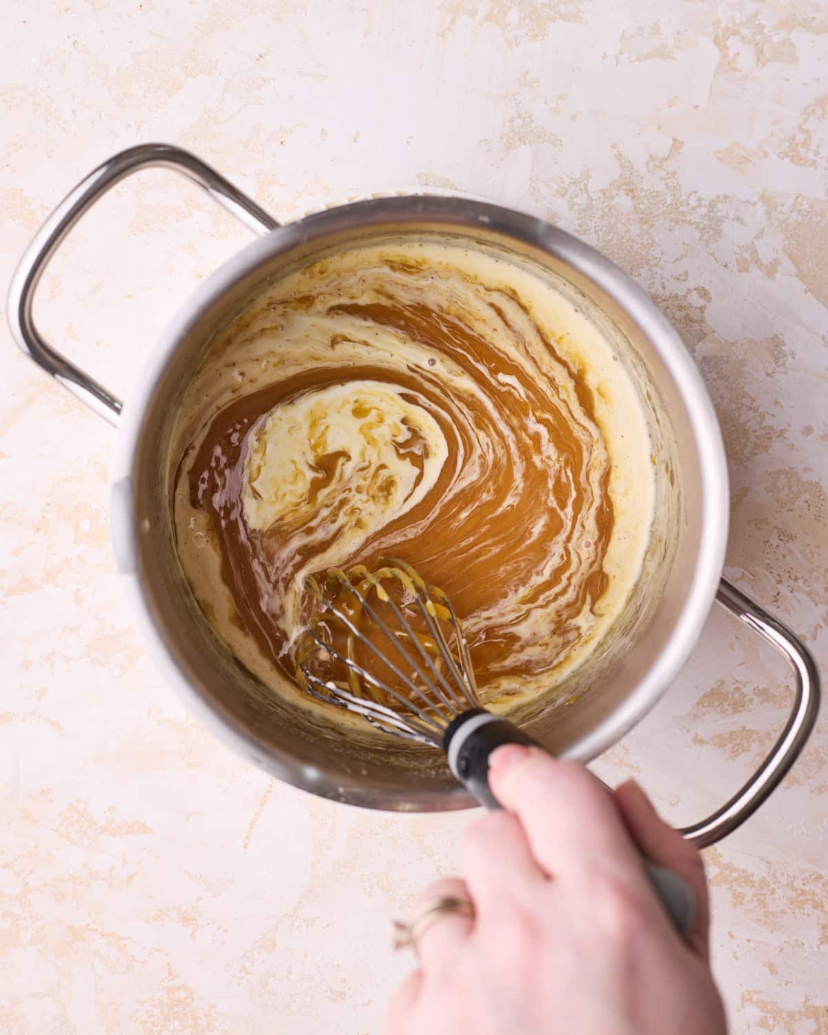 Whisking heavy cream into homemade caramel sauce.
