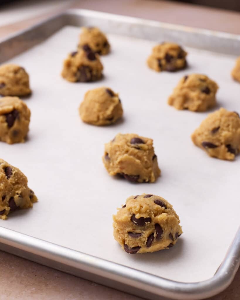 Side view of cookie dough balls spread out on a baking sheet, ready to be baked.