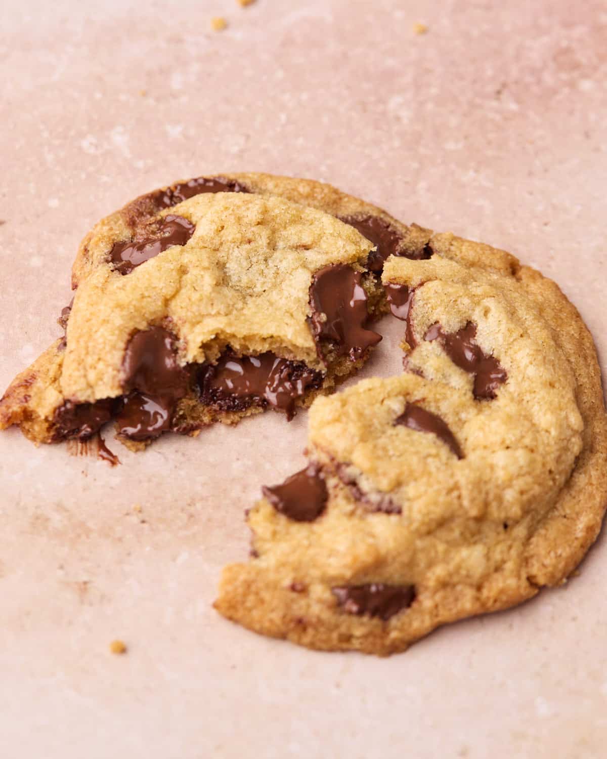 A chocolate chip cookie broken in two to show the gooey center.
