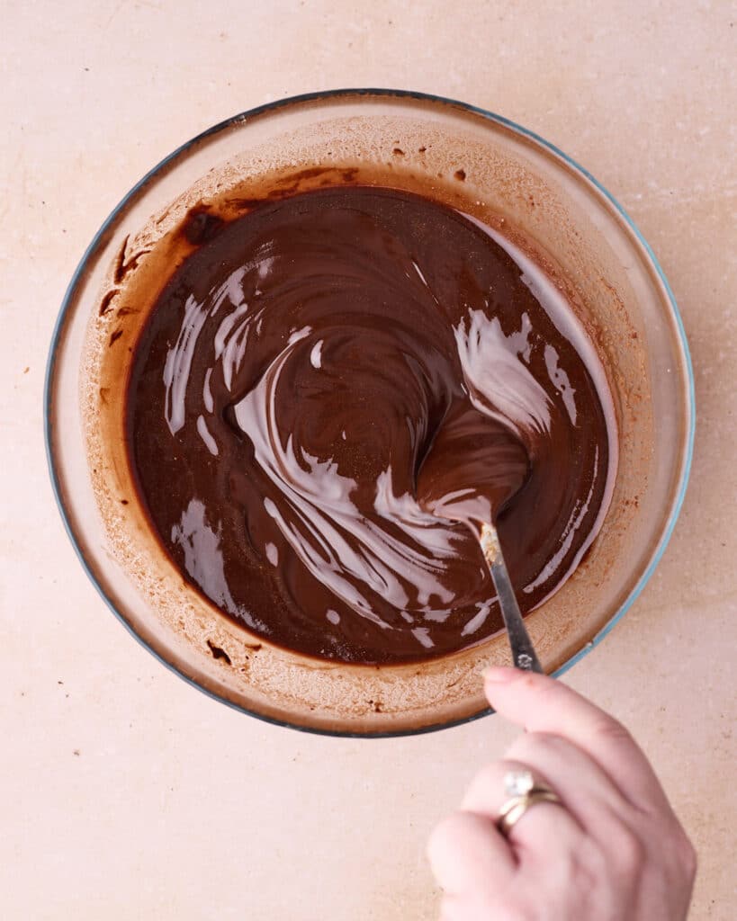 Melted chocolate being stirred in a heatproof bowl.
