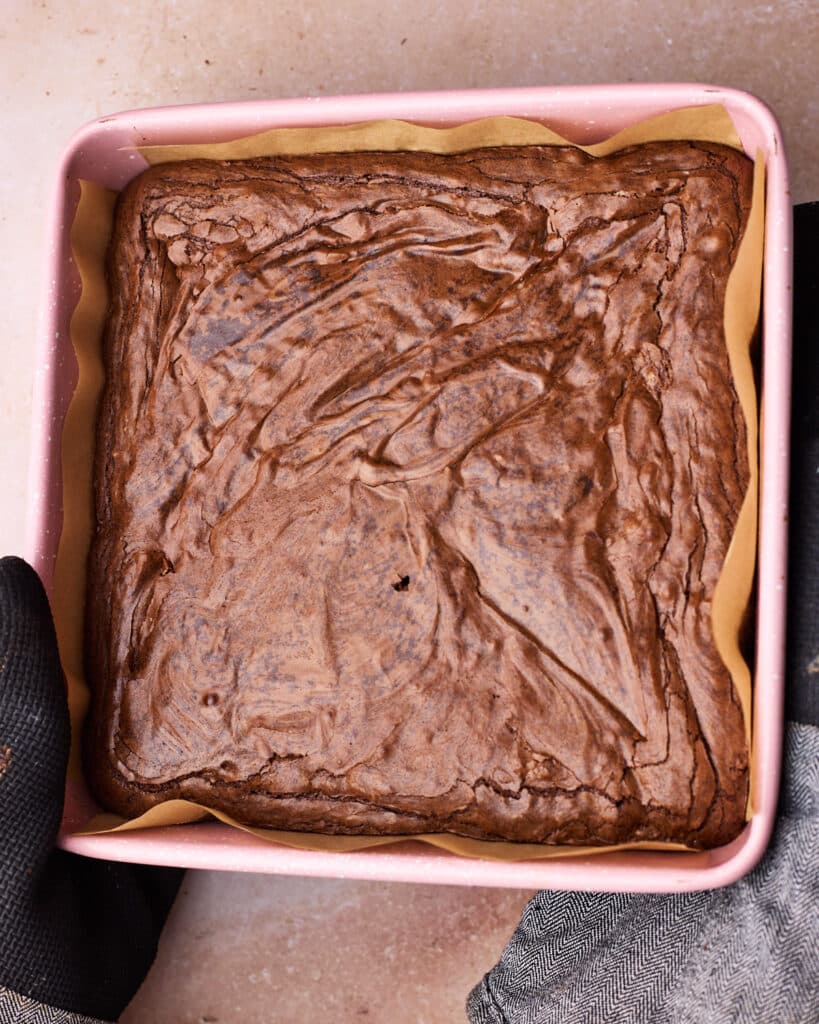 Freshly baked fudgy brownies in the pan, showing off the dry and shiny top.