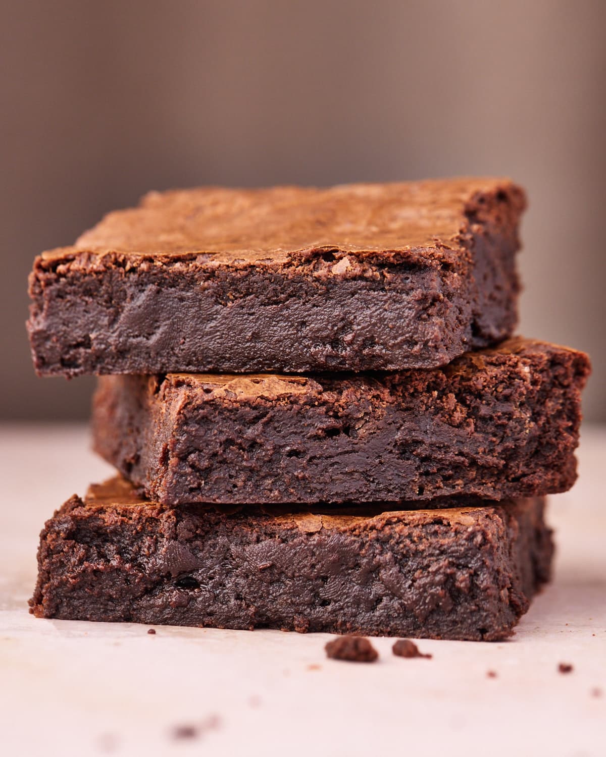 Side view of 3 fudgy brownies stacked on top of each other, showing off the gooey texture.