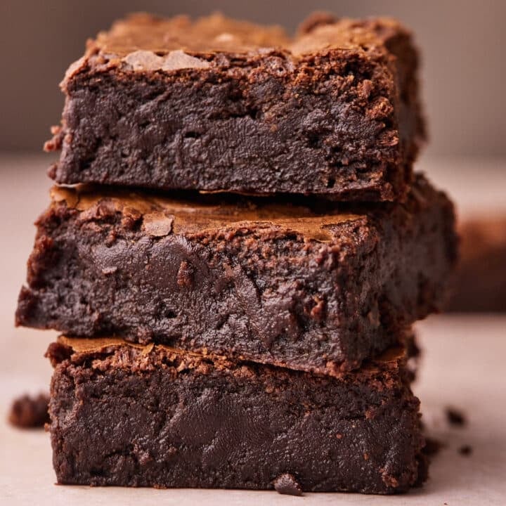 Side view of 3 thick fudgy brownies stacked on top of each other, showing off the gooey texture.