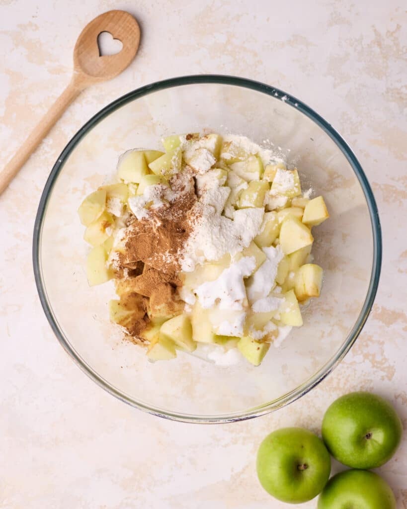 Sugar, flour, cinnamon and lemon juice added to the bowl of chopped apples.