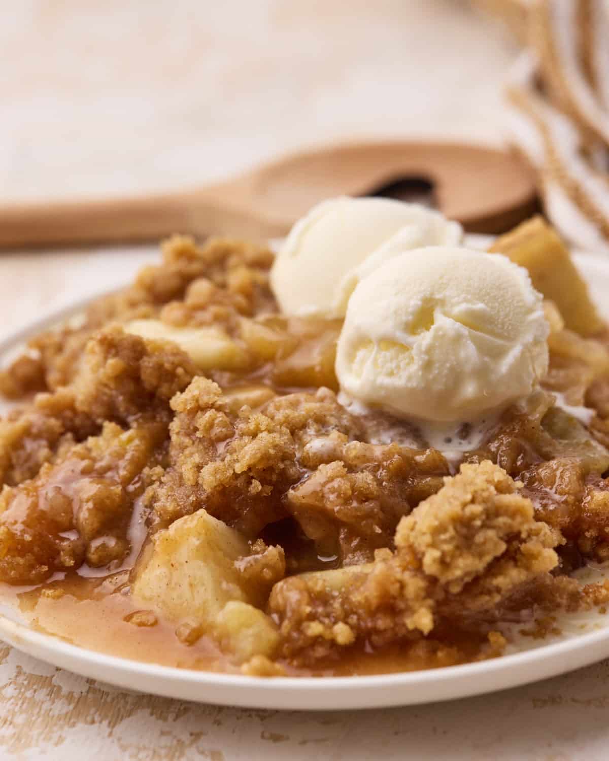 Close up of a portion of apple crumble on a plate with two scoops of ice cream on top.