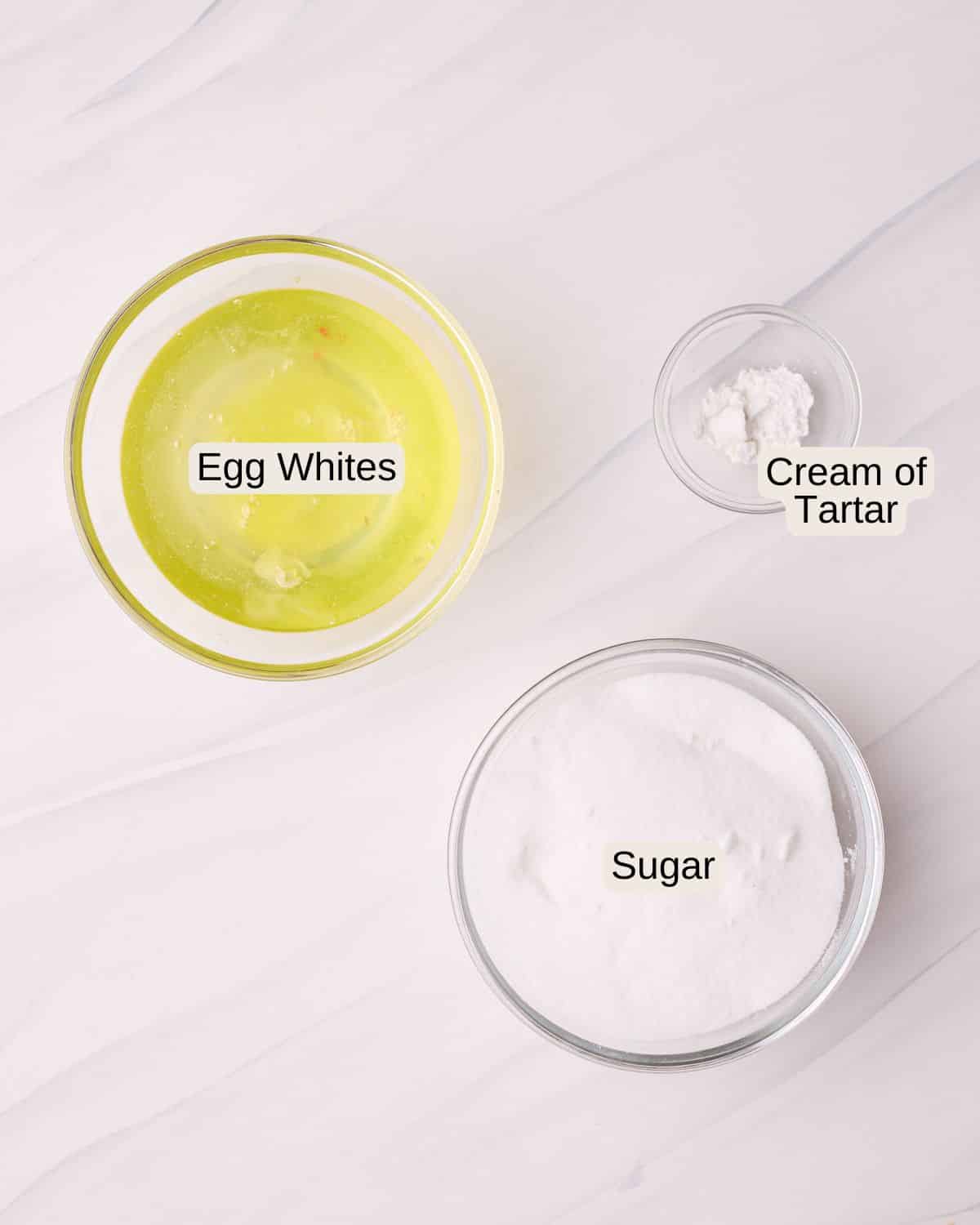Labelled ingredients for meringue cookies, including egg whites, sugar, and cream of tartar.