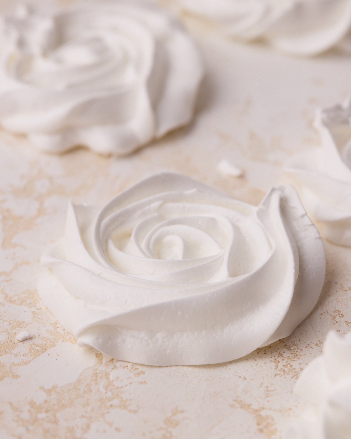 A close up of a white meringue cookies in the shape of a flat rose.