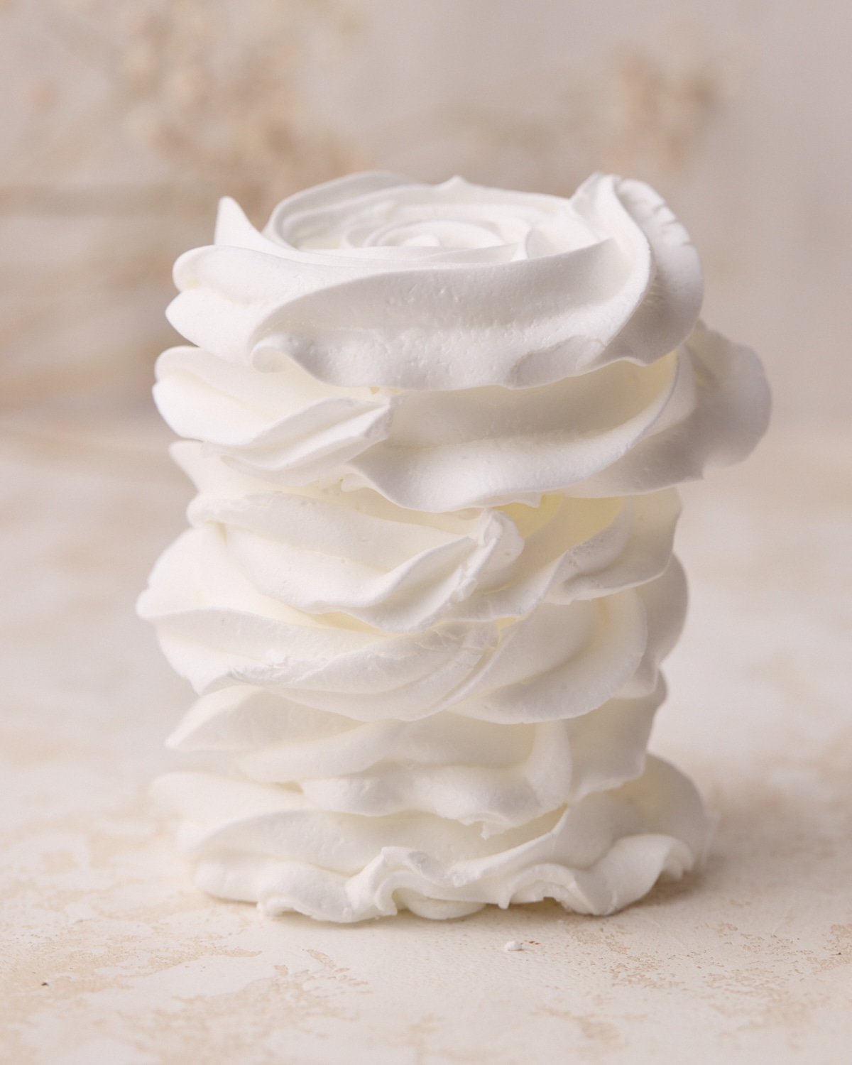 A stack of white meringue cookies in the shape of flat roses.