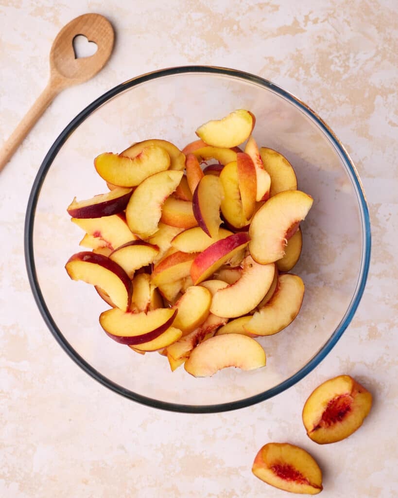 Fresh peaches cut into slices in a glass bowl. 