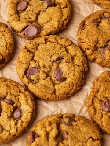 Close up of pumpkin chocolate chip cookies from above on a piece of parchment paper.