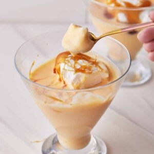 Creme anglaise in a glass serving dish, served with poached meringue and caramel.
