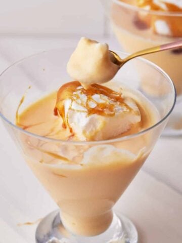 Creme anglaise in a glass serving dish, served with poached meringue and caramel.