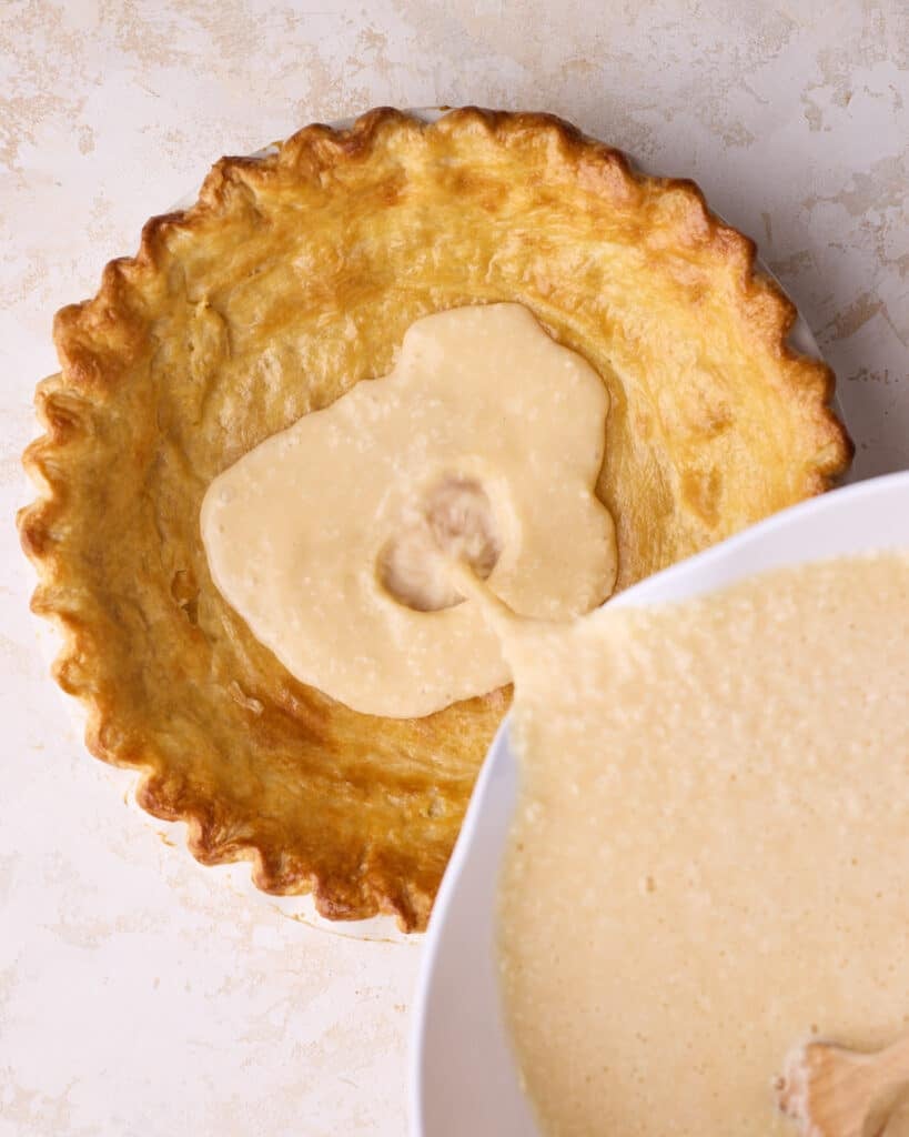 Coconut custard filling being poured into pie crust.