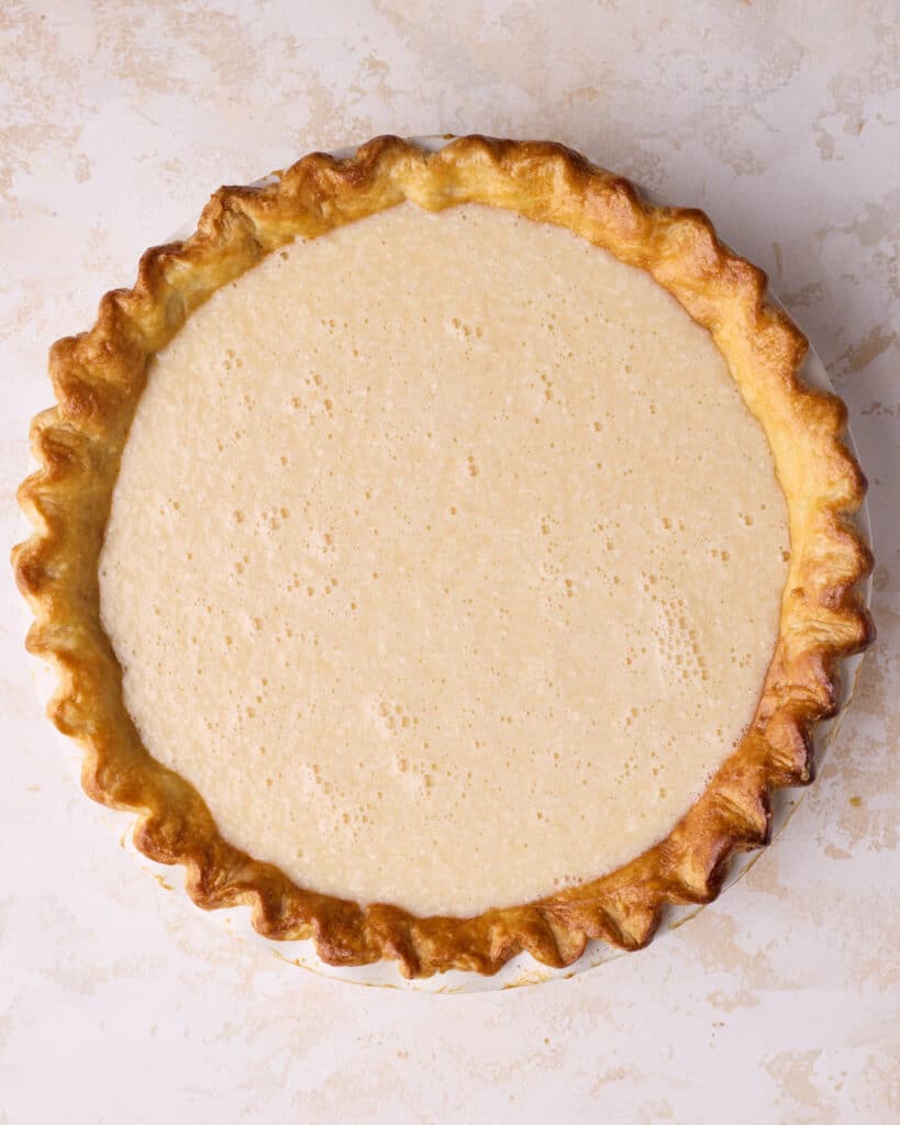Pie crust filled with coconut custard filling, ready to be baked.
