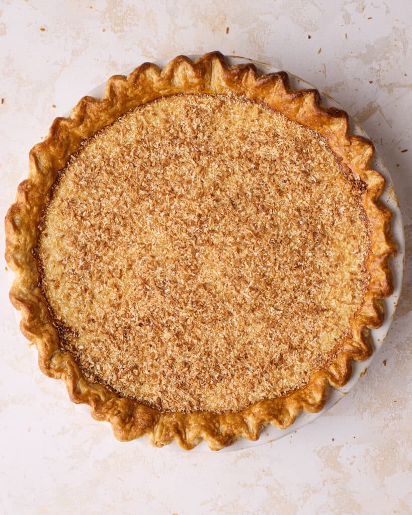Baked coconut custard pie covered in toasted coconut shreds.