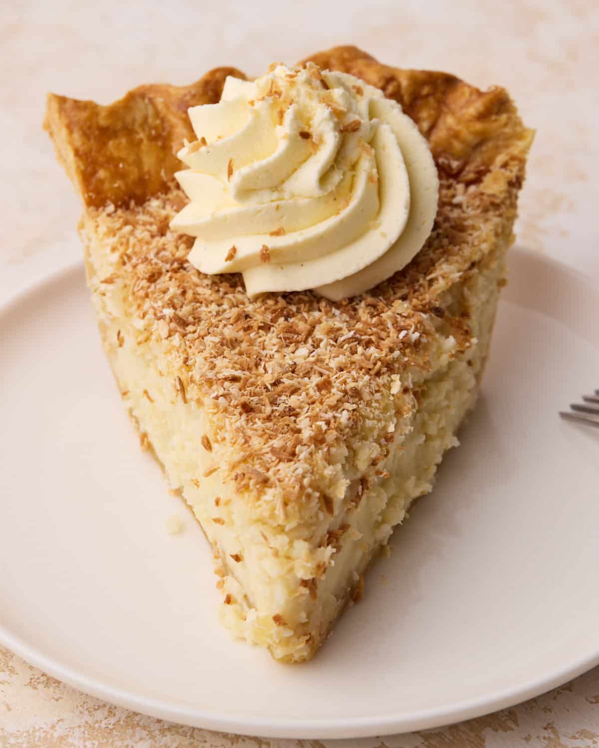 Front on close up of a slice of coconut custard pie on a plate.