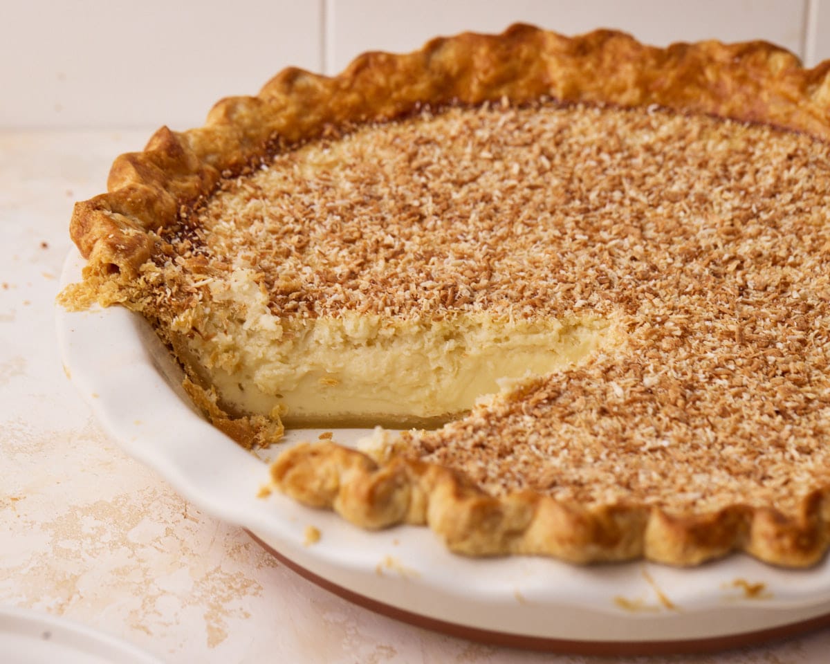 Coconut custard pie in a dish with a slice missing.
