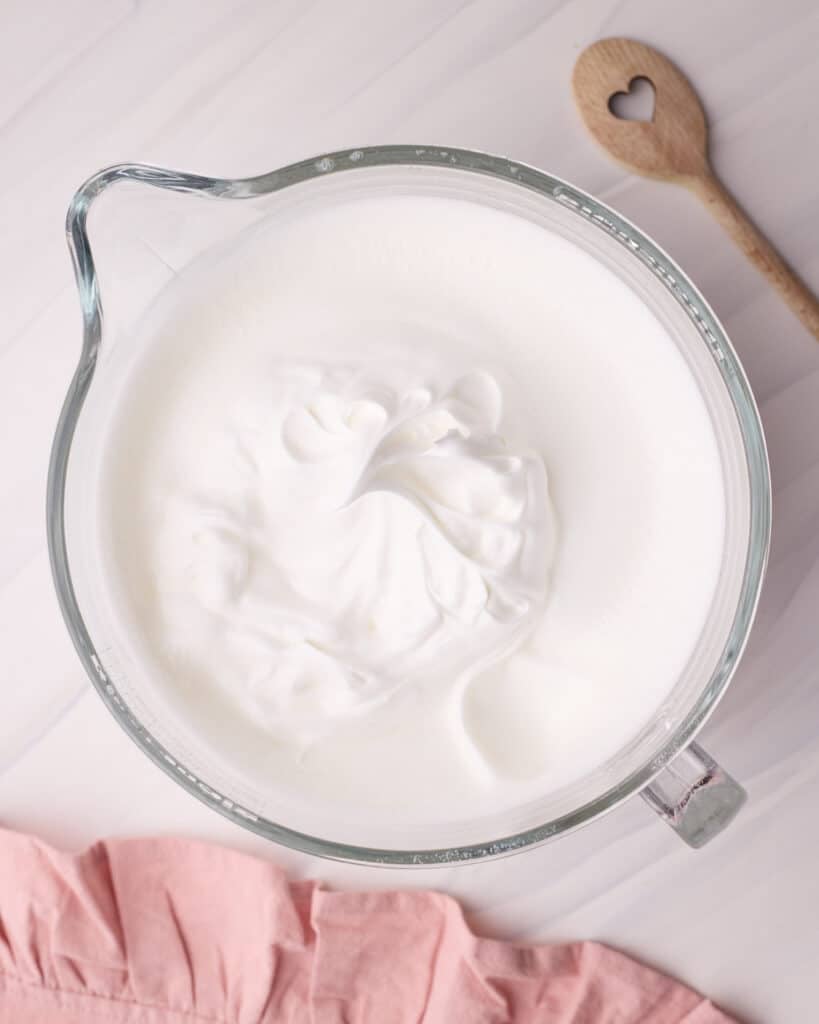 Meringue in a glass mixing bowl, whipped to firm peaks to make angel food cake.