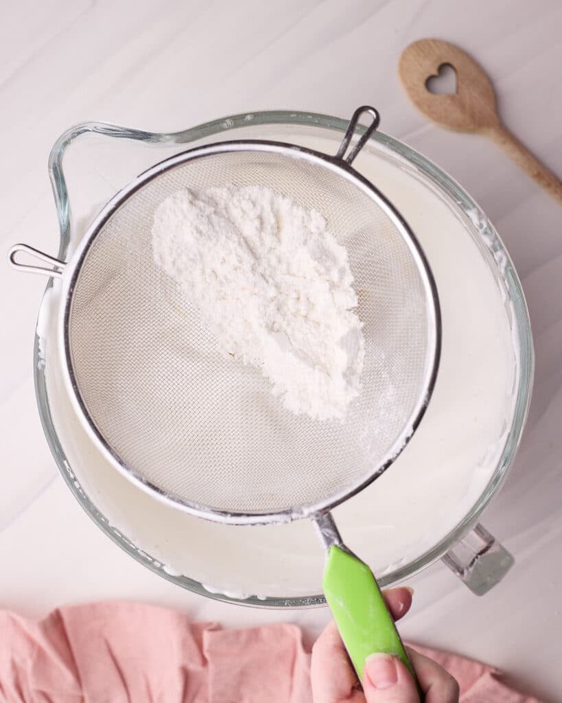Sifting flour into angel food cake batter to keep it light and airy.