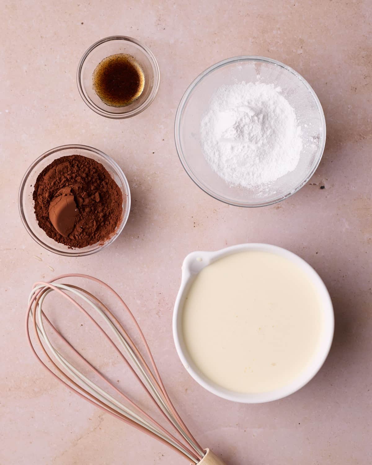Ingredients to make chocolate whipped cream, including heavy cream, powdered sugar, cocoa powder and vanilla.