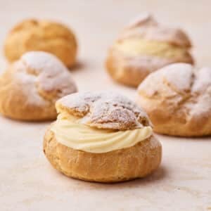 Four choux pastry buns sliced in half and filled with a swirl of creme diplomat.